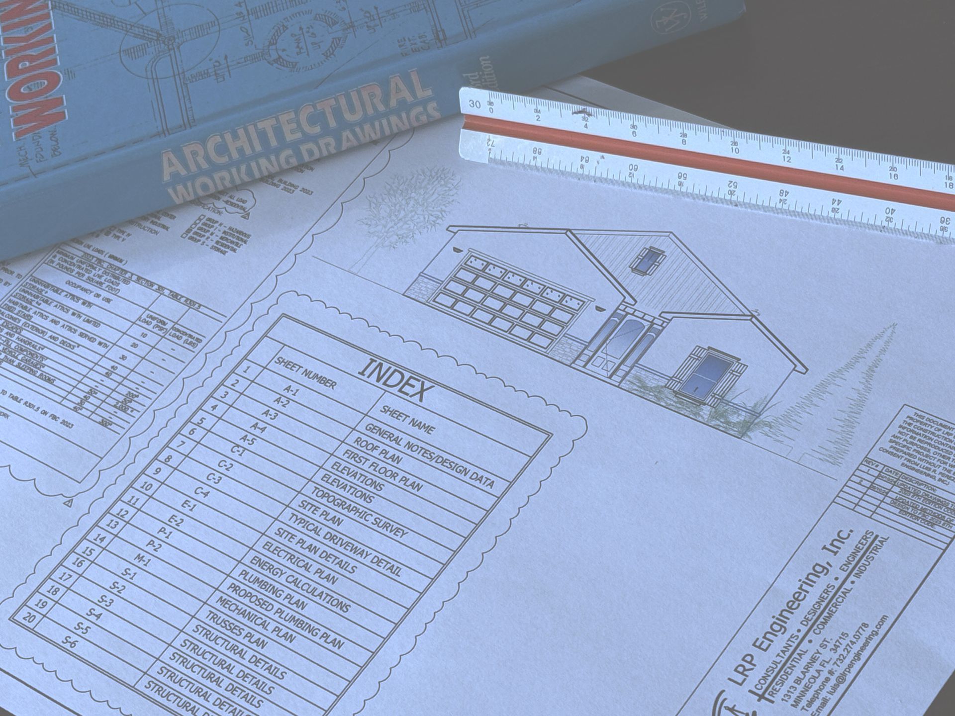 Architectural blueprints with a house sketch, index, scale ruler, and a book titled 