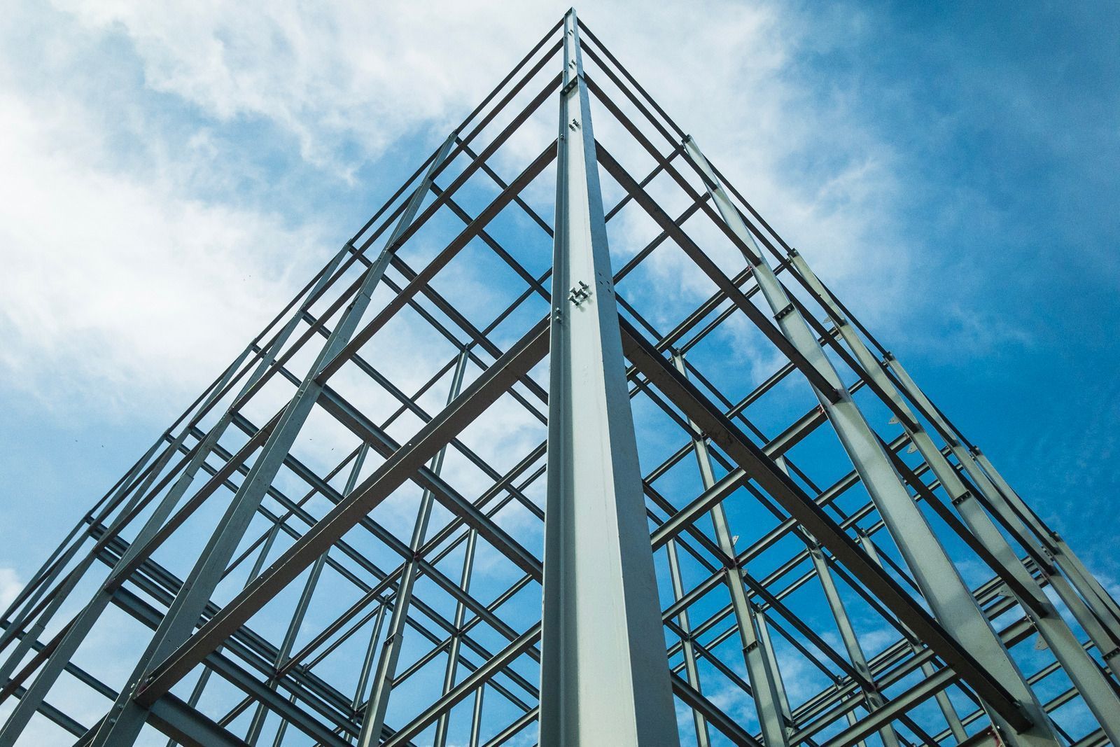 Steel framework of a building against a cloudy blue sky.