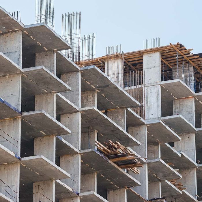 Construction site with concrete framework and exposed rebar, under a blue sky.