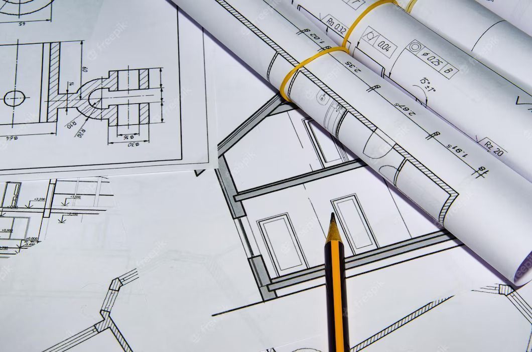 Architectural blueprints with a pencil, rolled and laid out.