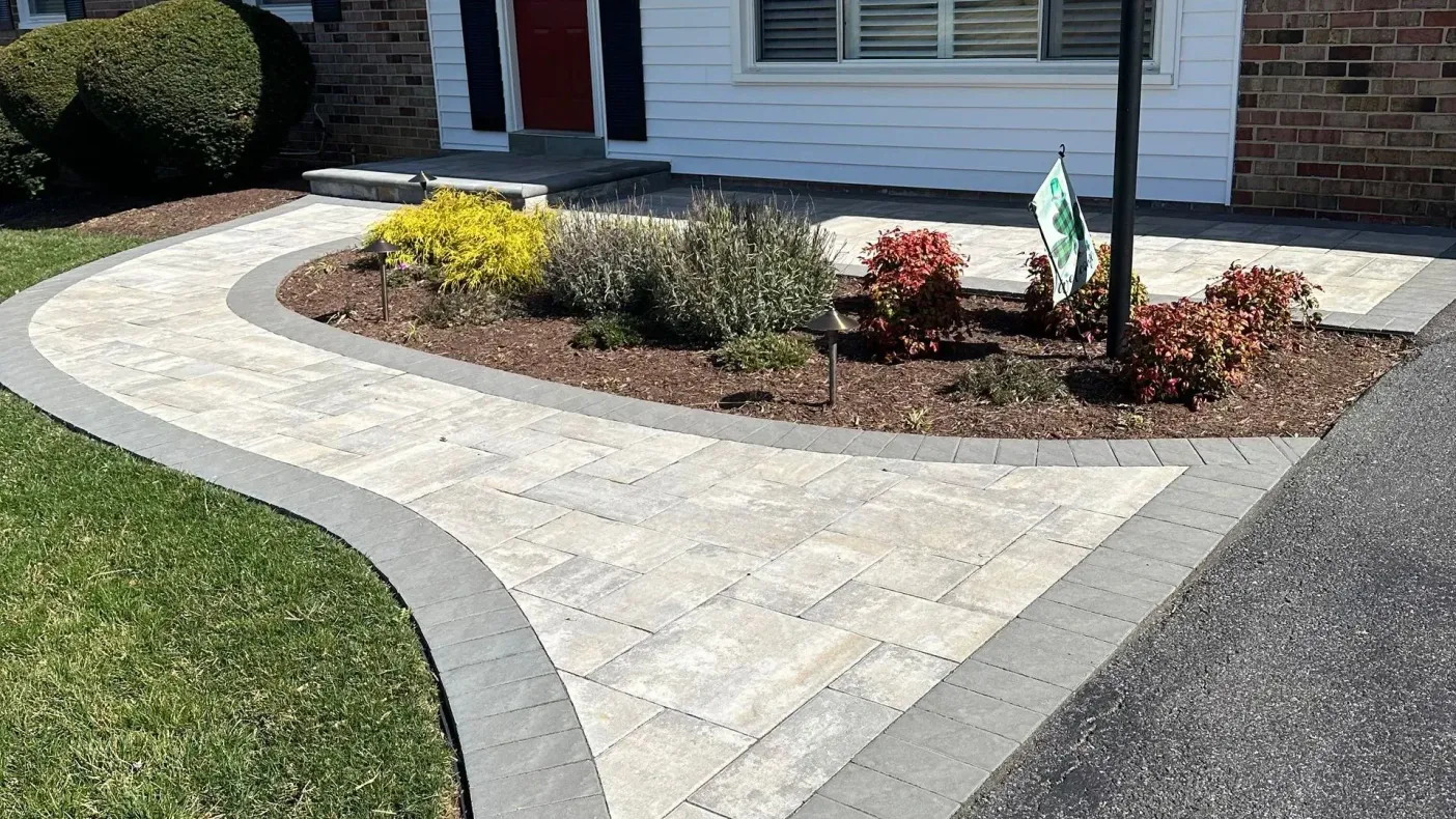 Curved concrete walkway leading to a home’s front entrance with landscaped garden beds Curved concrete walkway leading to a home’s front entrance with landscaped garden beds