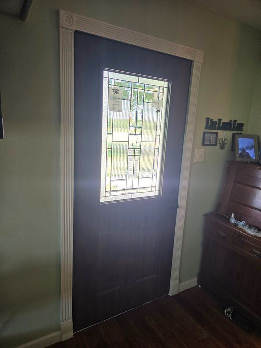 Brown front door with frosted glass panels set in a white wall, with a silver handle and lock