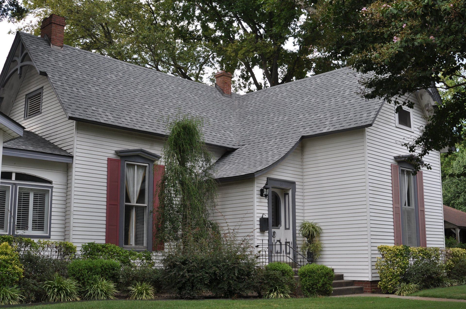 A white house with a gray roof and red shutters