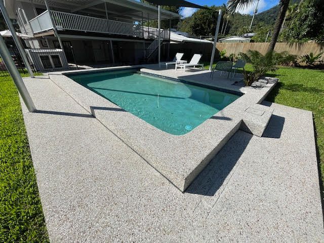 Modern backyard pool with concrete deck, built-in steps, and lawn landscaping