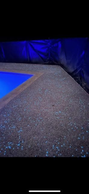 Blue-lit poolside walkway beside dark water or liner at night