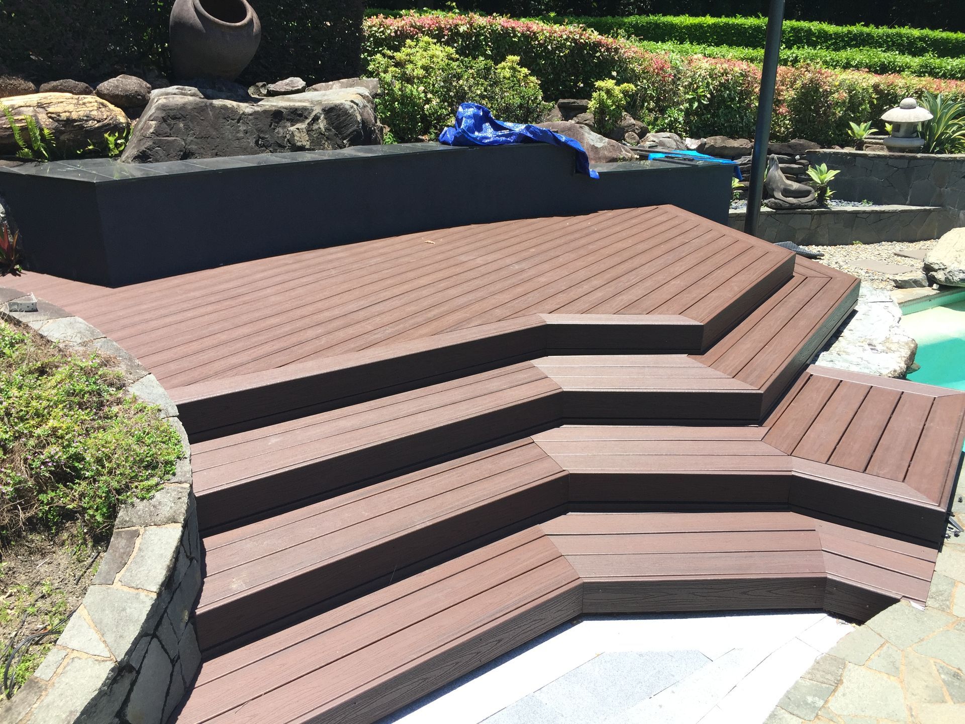 Tiered composite decking raised patio area beside pool installed