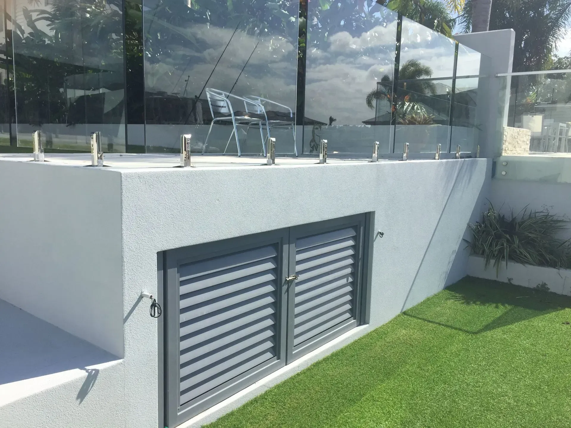 Engineered retaining wall supporting an elevated outdoor area with glass balustrade in Cairns