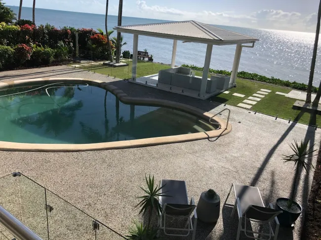 Exposed aggregate concrete around swimming pool and outdoor gazebo