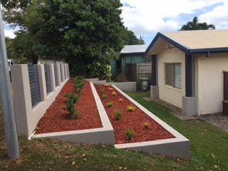Raised red gravel garden beds installed behind new besser block retaining wall