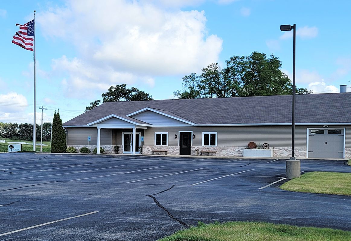 Single-story building with parking lot and American flag on a cloudy day