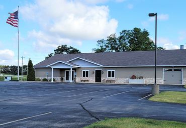 Single-story building with parking lot and American flag on a cloudy day