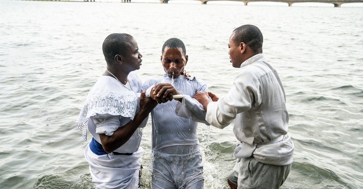 A man is being baptised by two other men in the water.