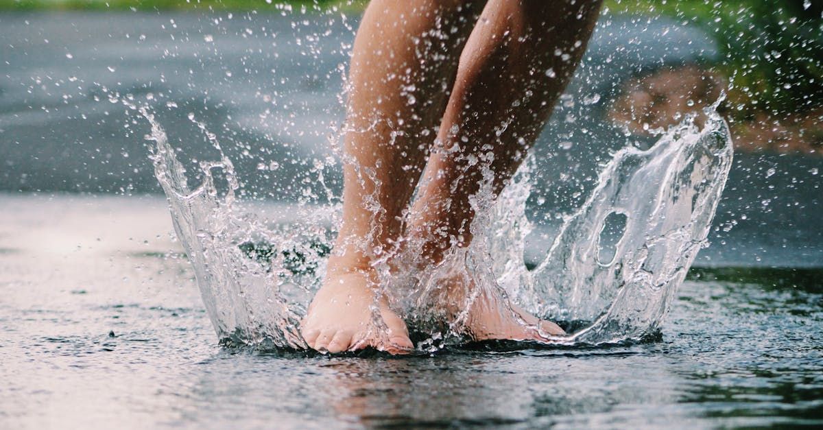 A person 's feet are splashing in a puddle of water.