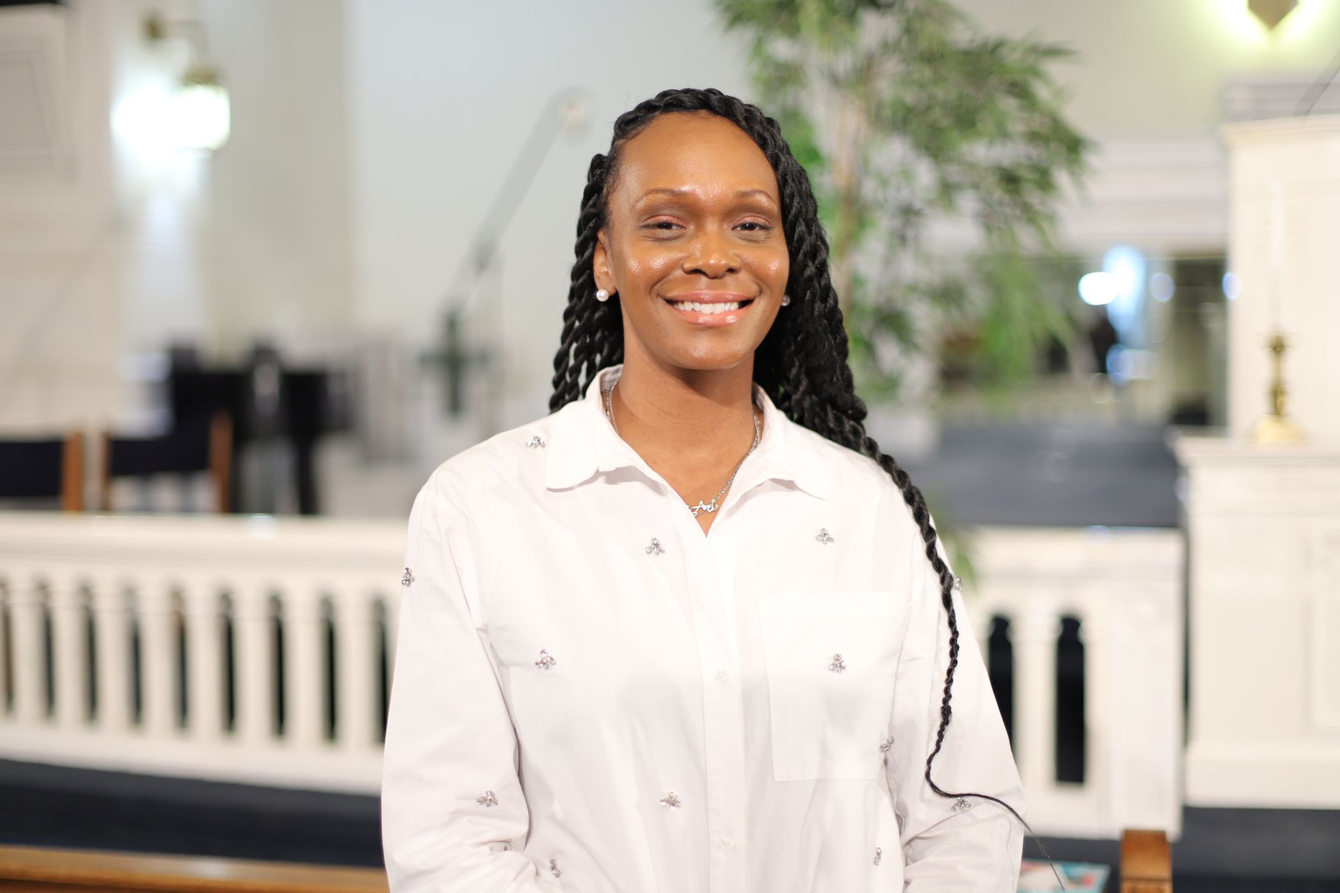 A woman in a white shirt is smiling in a church.