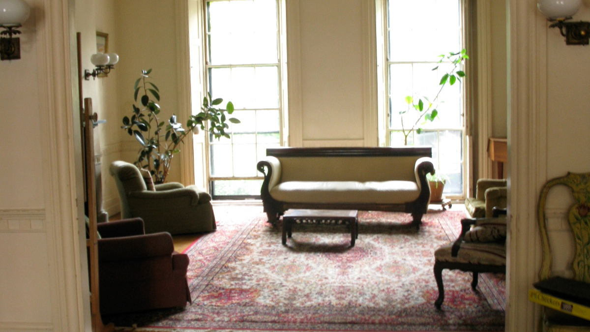 Living room with antique furniture, large windows, and a patterned rug.