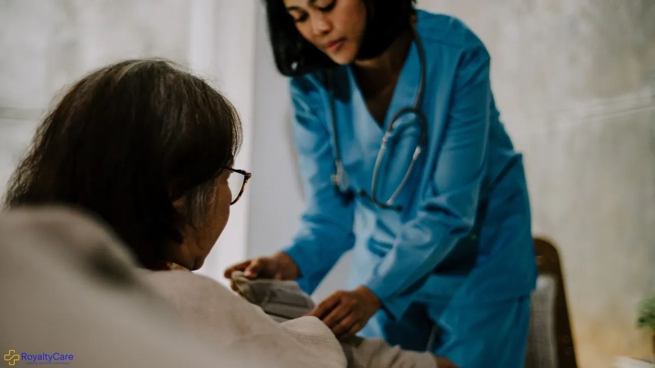 Healthcare worker in blue uniform assisting a patient in bed with a medical device