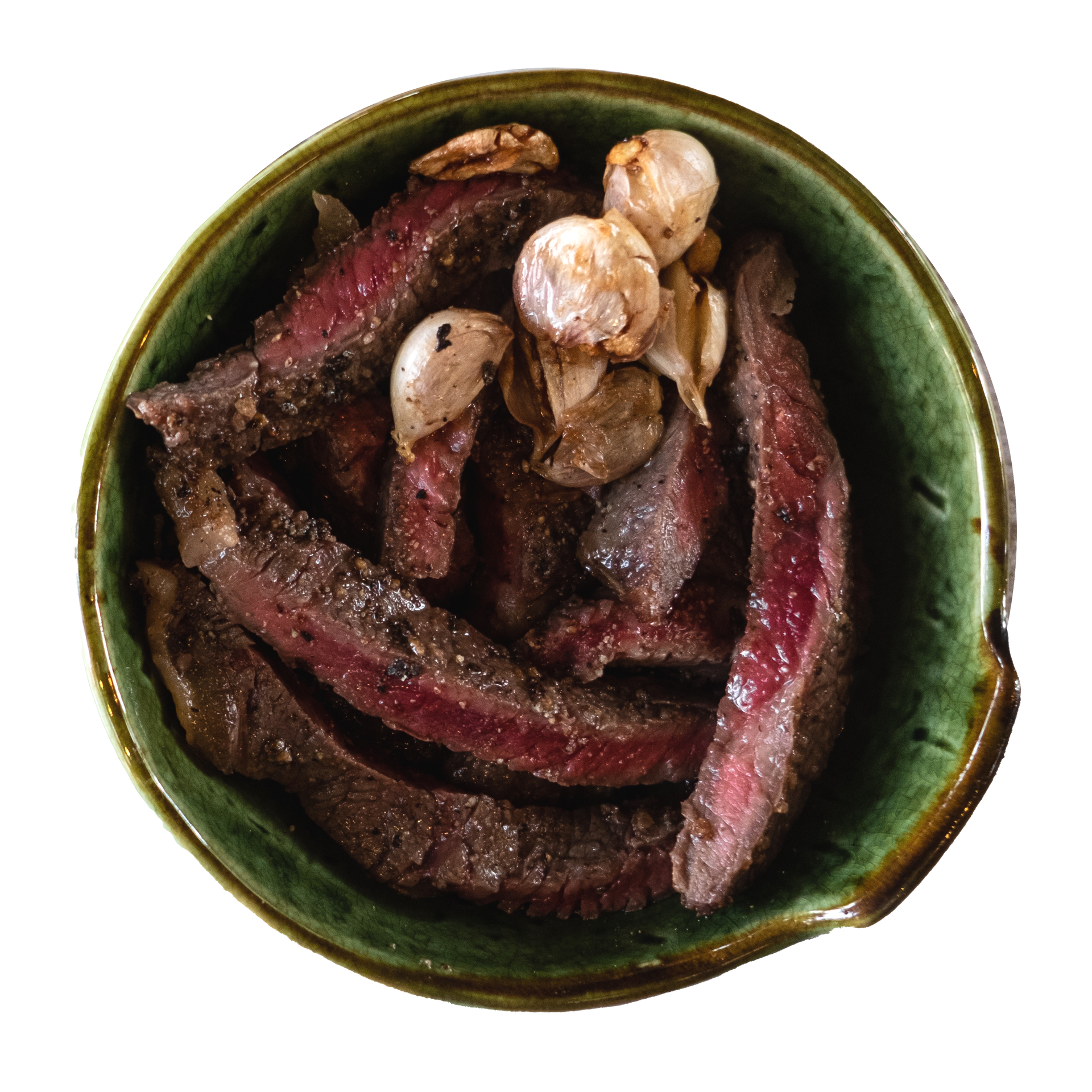 JPOT Japanese BBQ cut up and sliced medium rare galbi short ribs with garlic cloves in a green ceramic bowl bird's eye view