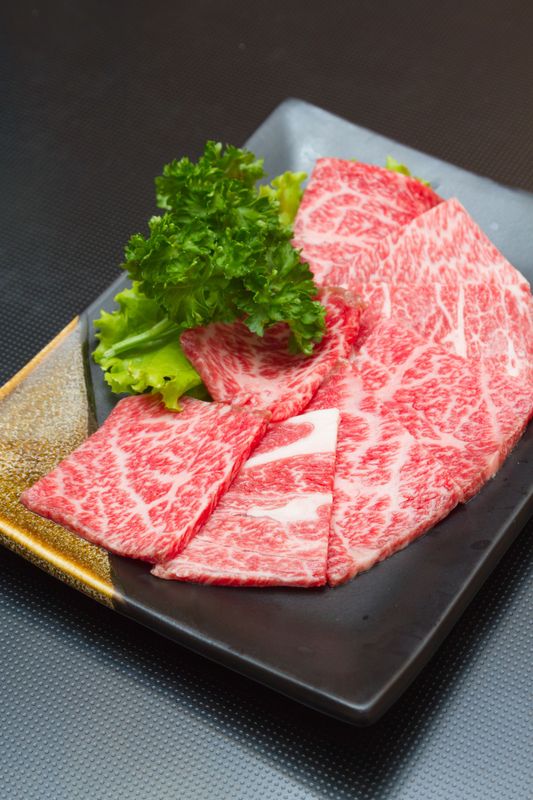 JPOT Japanese hot pot and BBQ thinly sliced marbled beef on a gold and black rectangular plate