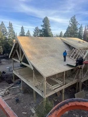 A man is standing on the roof of a house under construction.
