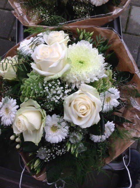 Ein Strauß weißer Blumen ist in braunes Papier eingewickelt