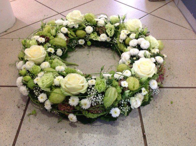 Ein Kranz aus weißen und grünen Blumen auf einem gefliesten Boden