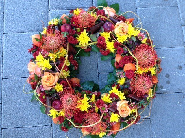 Ein Blumenkranz liegt auf einem gemauerten Gehweg