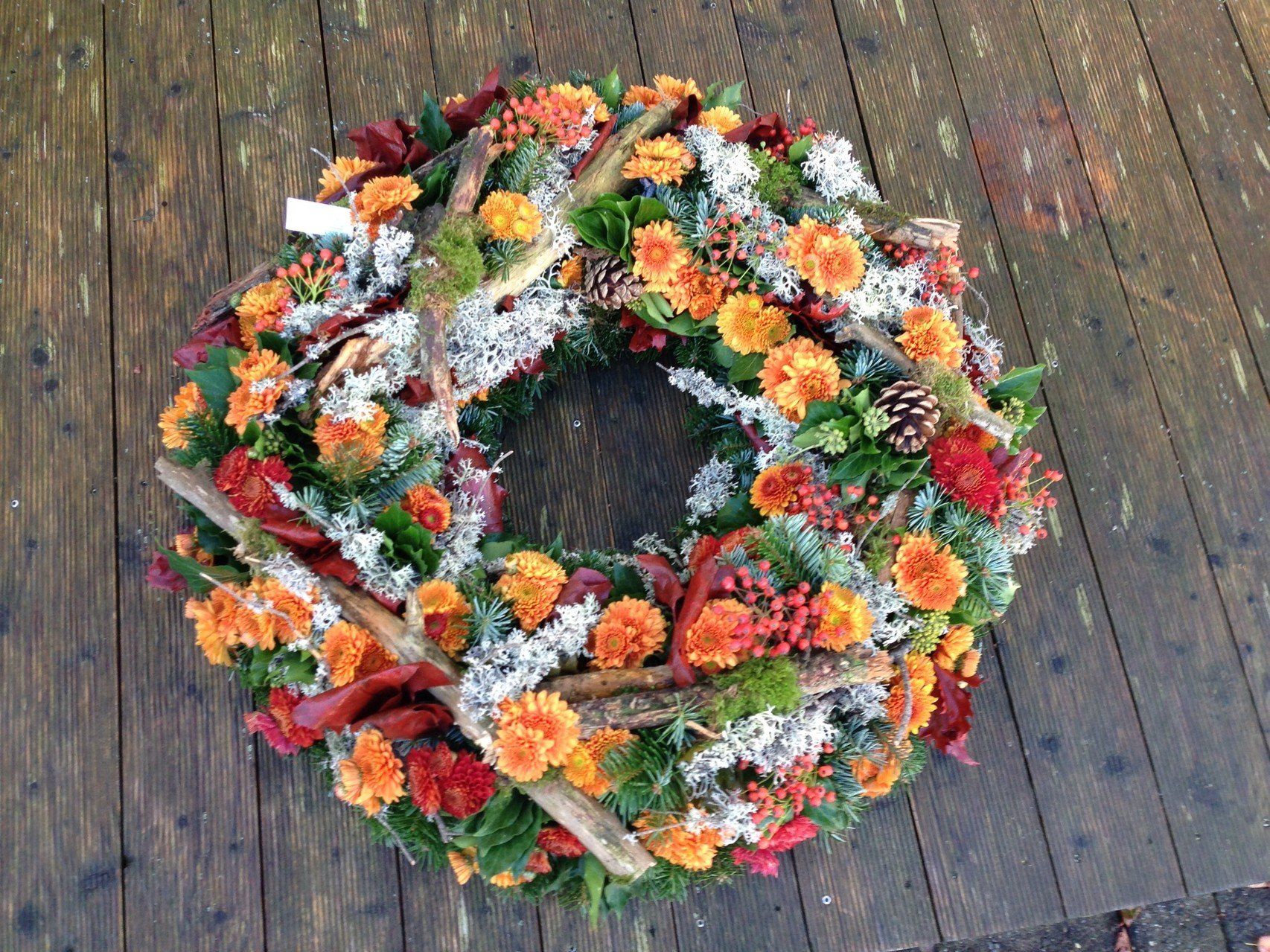 Auf einem Holztisch steht ein Blumenkranz.