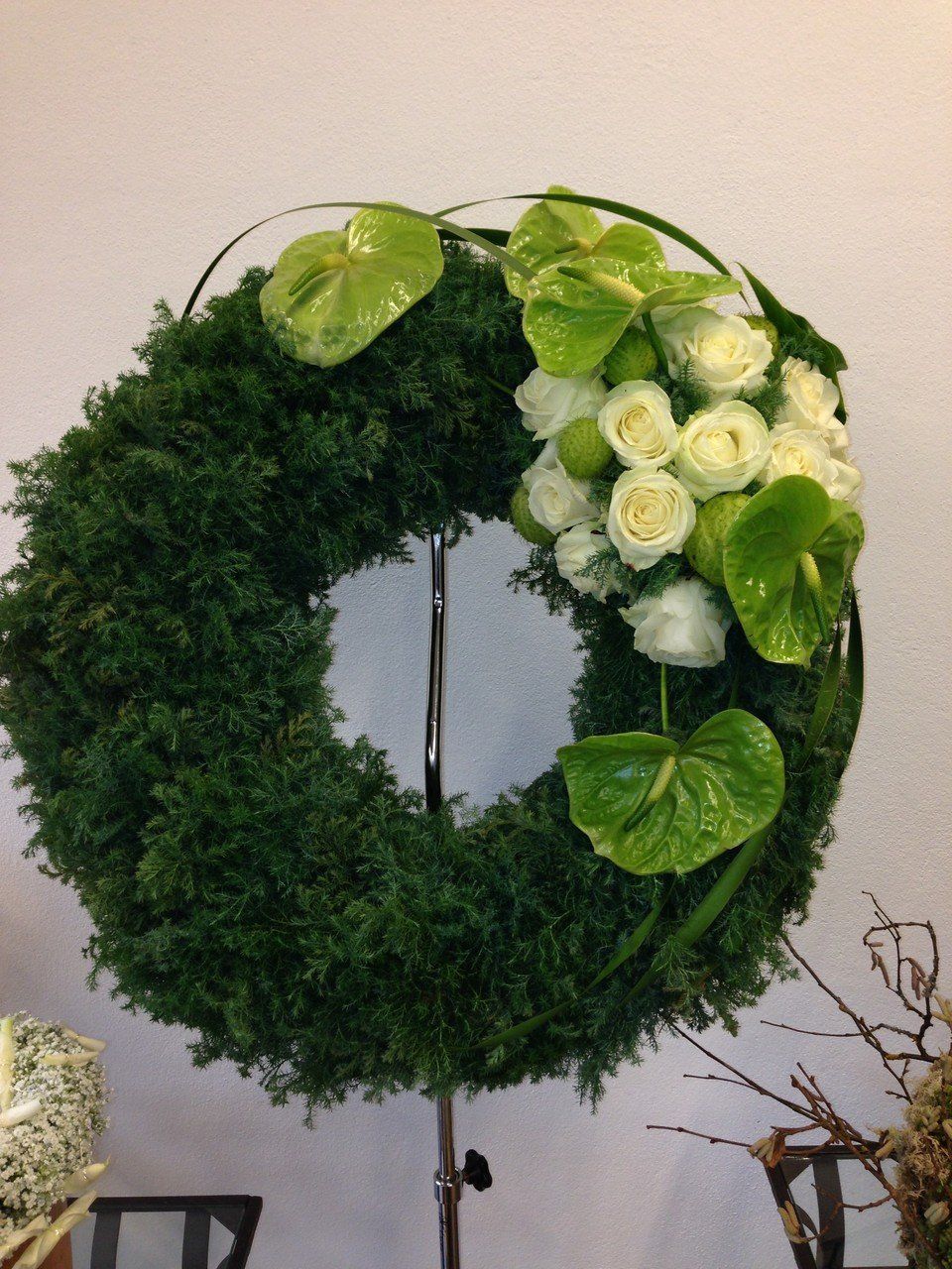 Ein grüner Kranz mit weißen Rosen und grünen Blättern