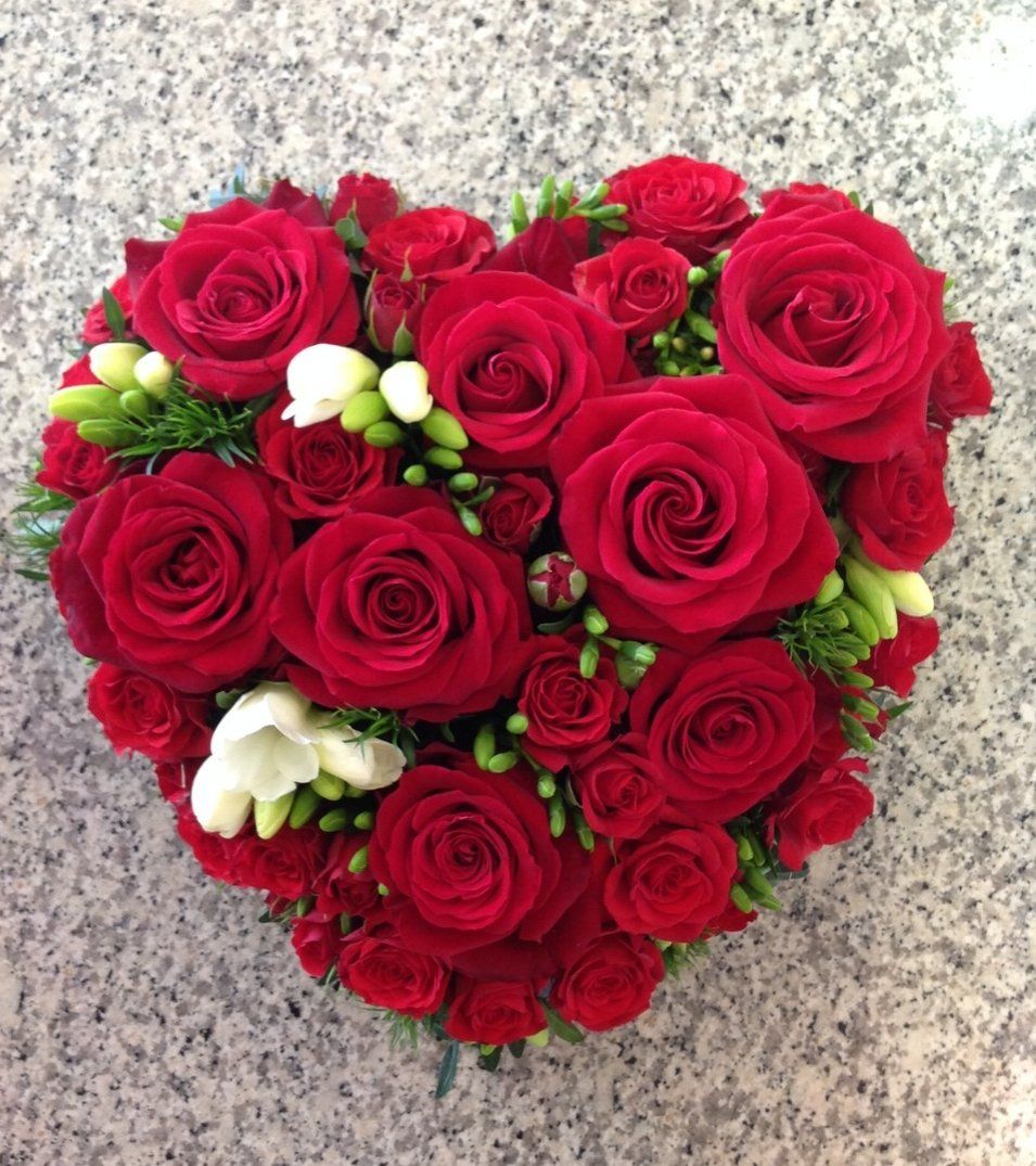 Ein herzförmiges Arrangement aus roten Rosen und Grünpflanzen