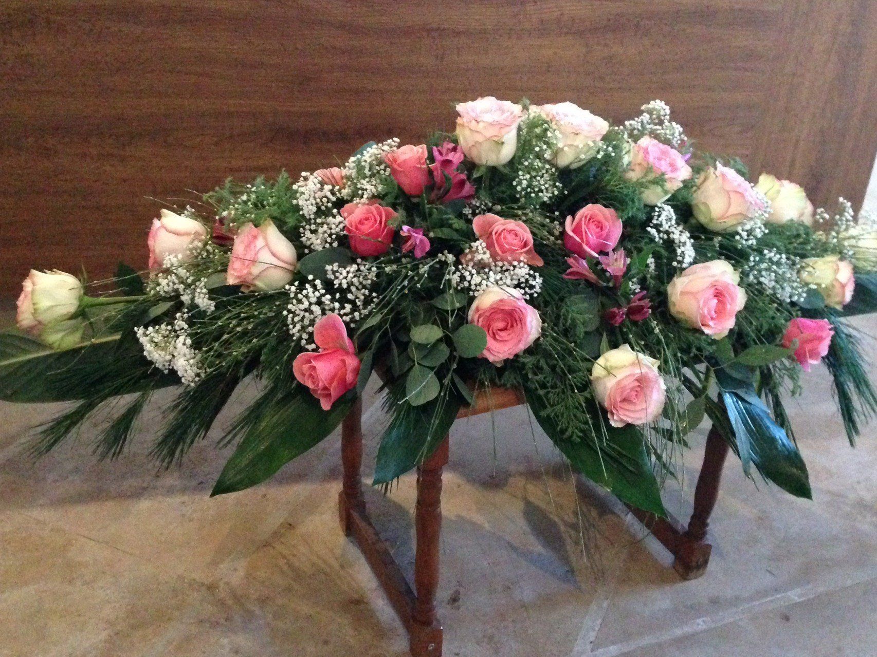 Ein Strauß rosa Rosen steht auf einem Holztisch.