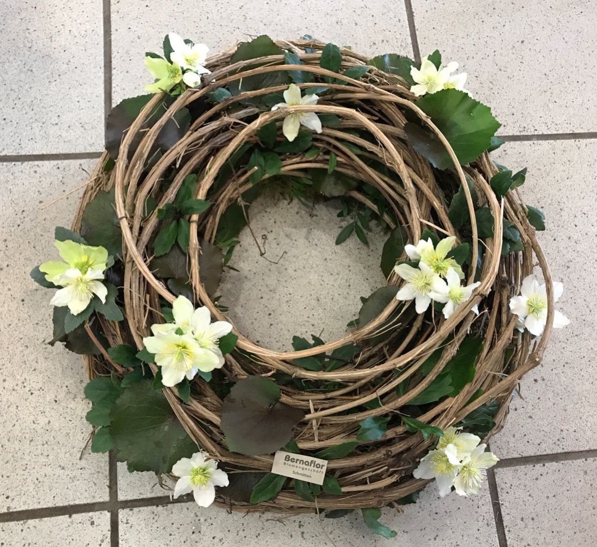 Ein Kranz mit weißen Blüten und grünen Blättern auf einem gefliesten Boden