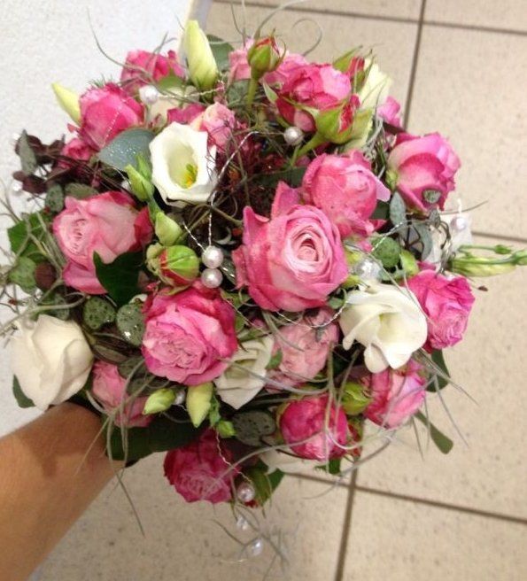 Eine Person hält einen Strauß rosa und weißer Blumen