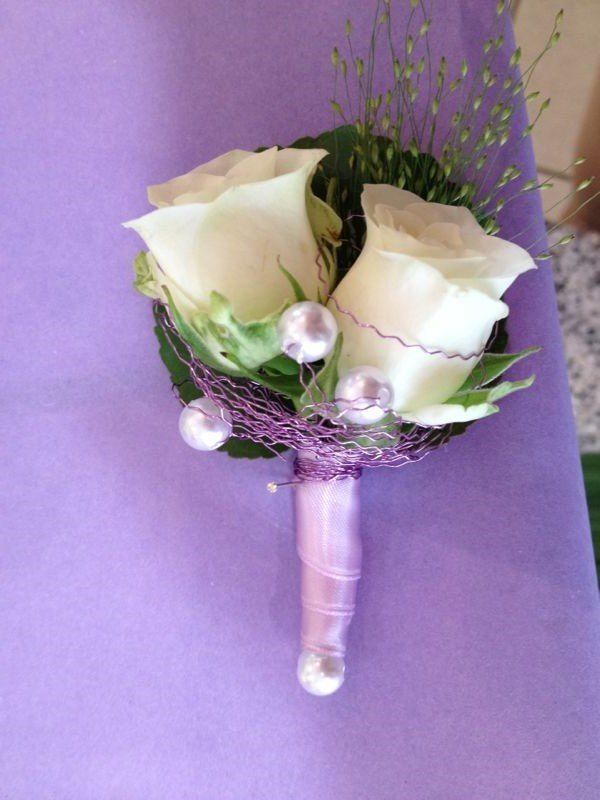Ein Strauß weißer Rosen mit Perlen auf einem lila Tuch