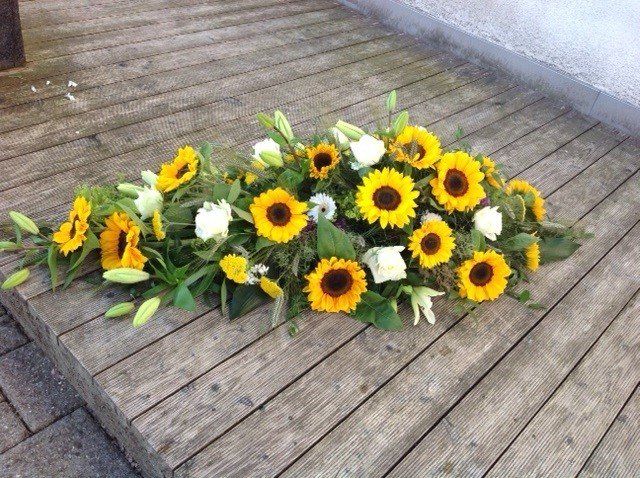 Ein Strauß Sonnenblumen steht auf einem Holzdeck.