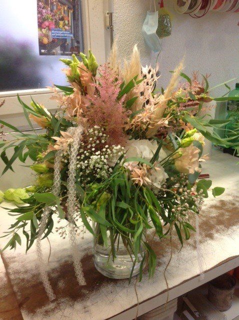 Auf einem Tisch steht eine mit Blumen gefüllte Vase.