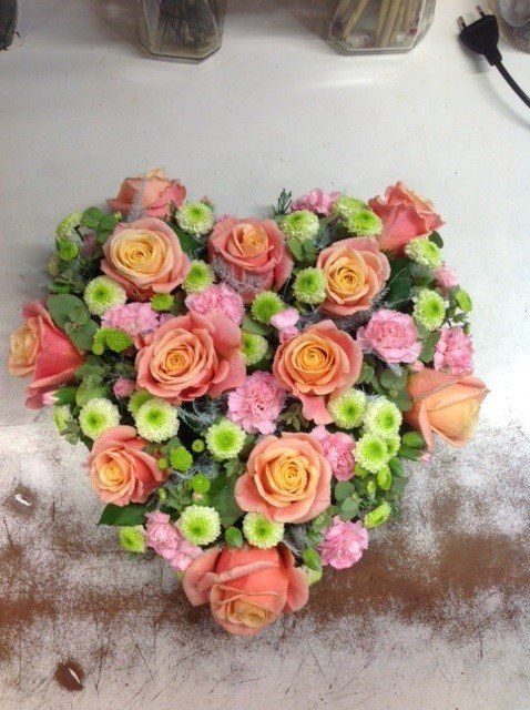 Ein herzförmiger Strauß aus rosa und grünen Blumen
