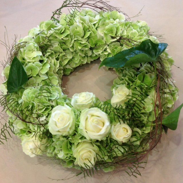 Ein Kranz aus grünen Blumen und weißen Rosen