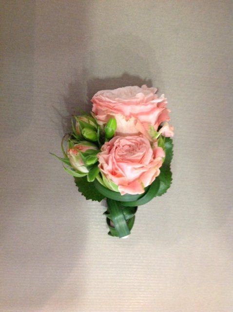 Eine Nahaufnahme einer rosa Rose mit grünen Blättern auf einem Tisch.