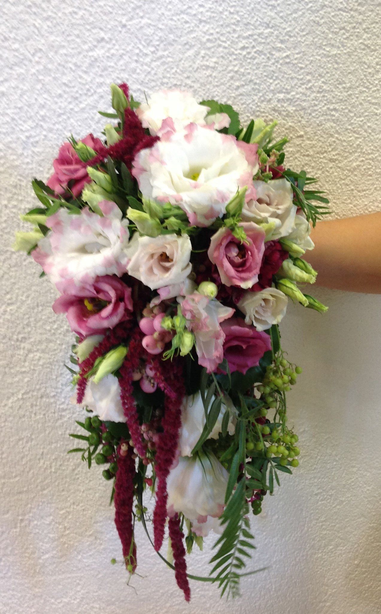 Eine Person hält einen Strauß rosa und weißer Blumen in der Hand.