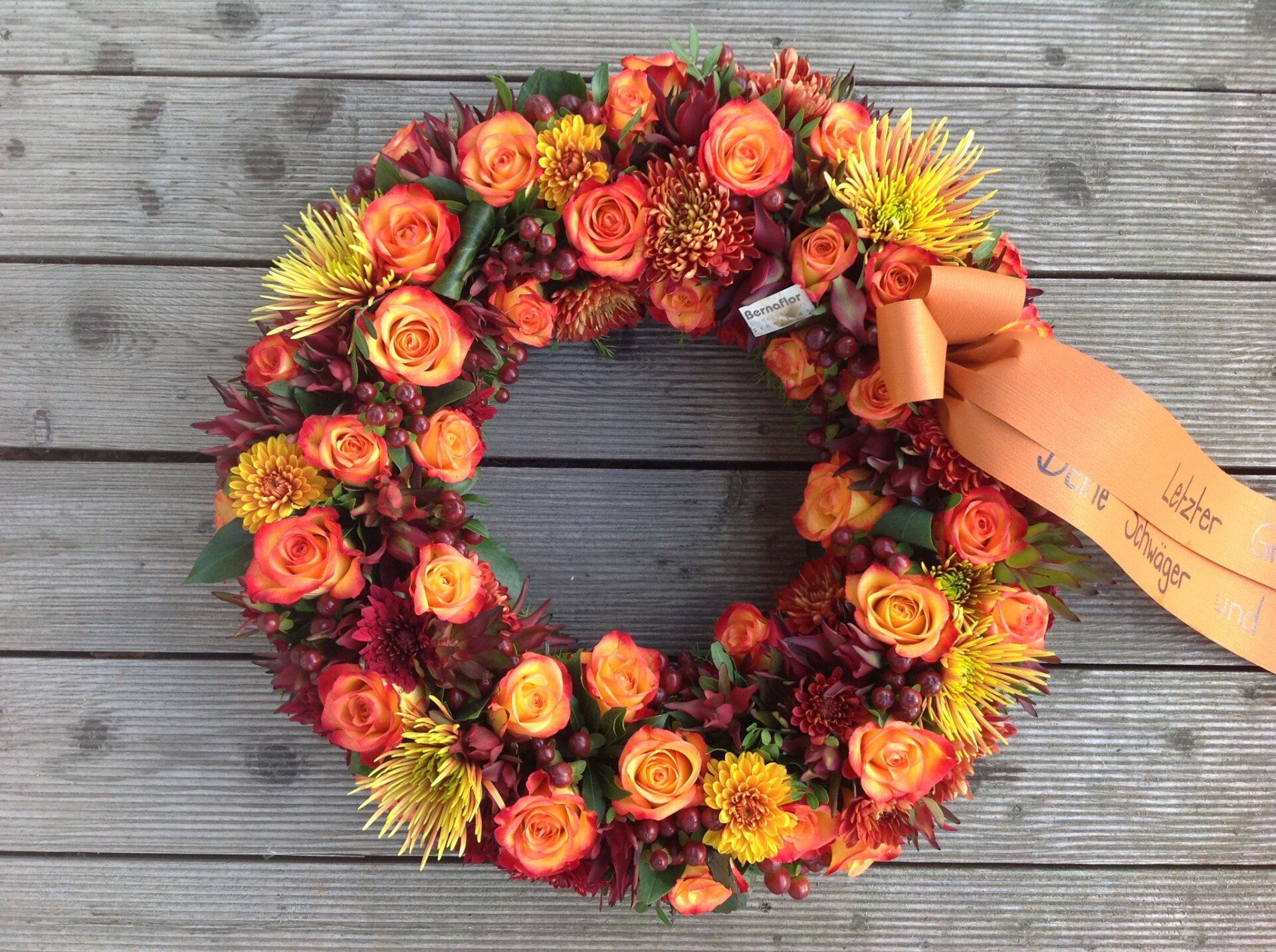 Auf einem Holztisch steht ein Blumenkranz.