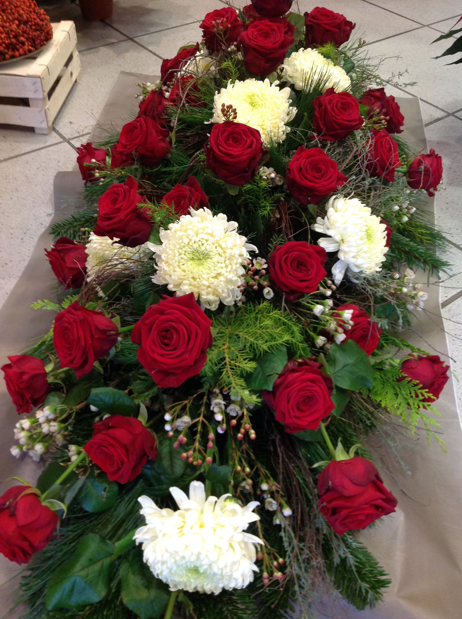 Ein langer Strauß roter Rosen und weißer Blumen auf einem Tisch.