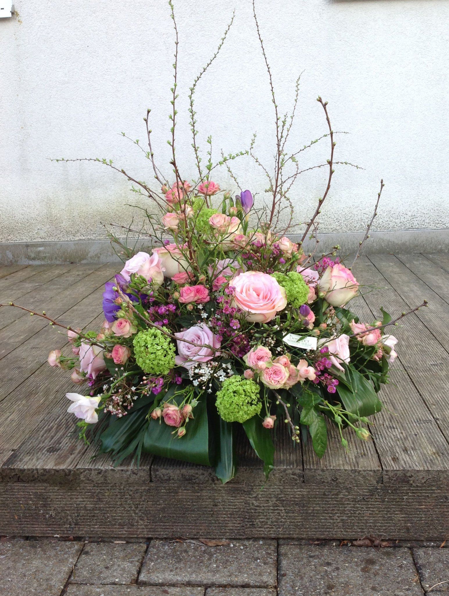 Auf einem gepflasterten Gehweg steht ein großer Blumenstrauß.