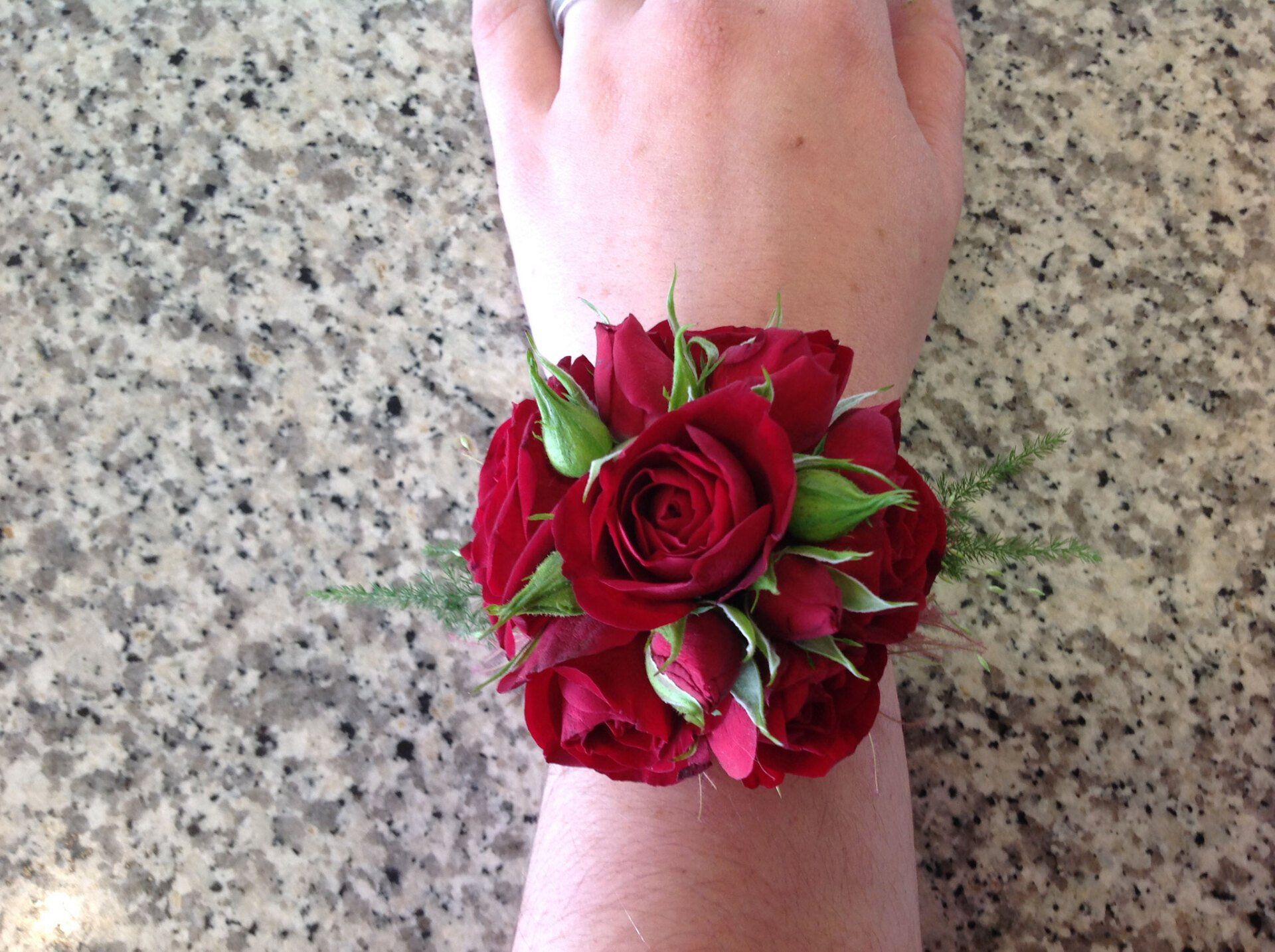 Eine Person trägt ein Armband mit roten Rosen darauf.