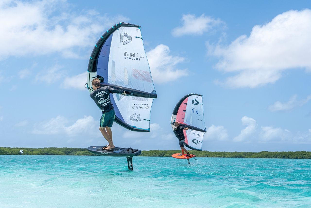 Two people are flying kites in the ocean in the caribbean