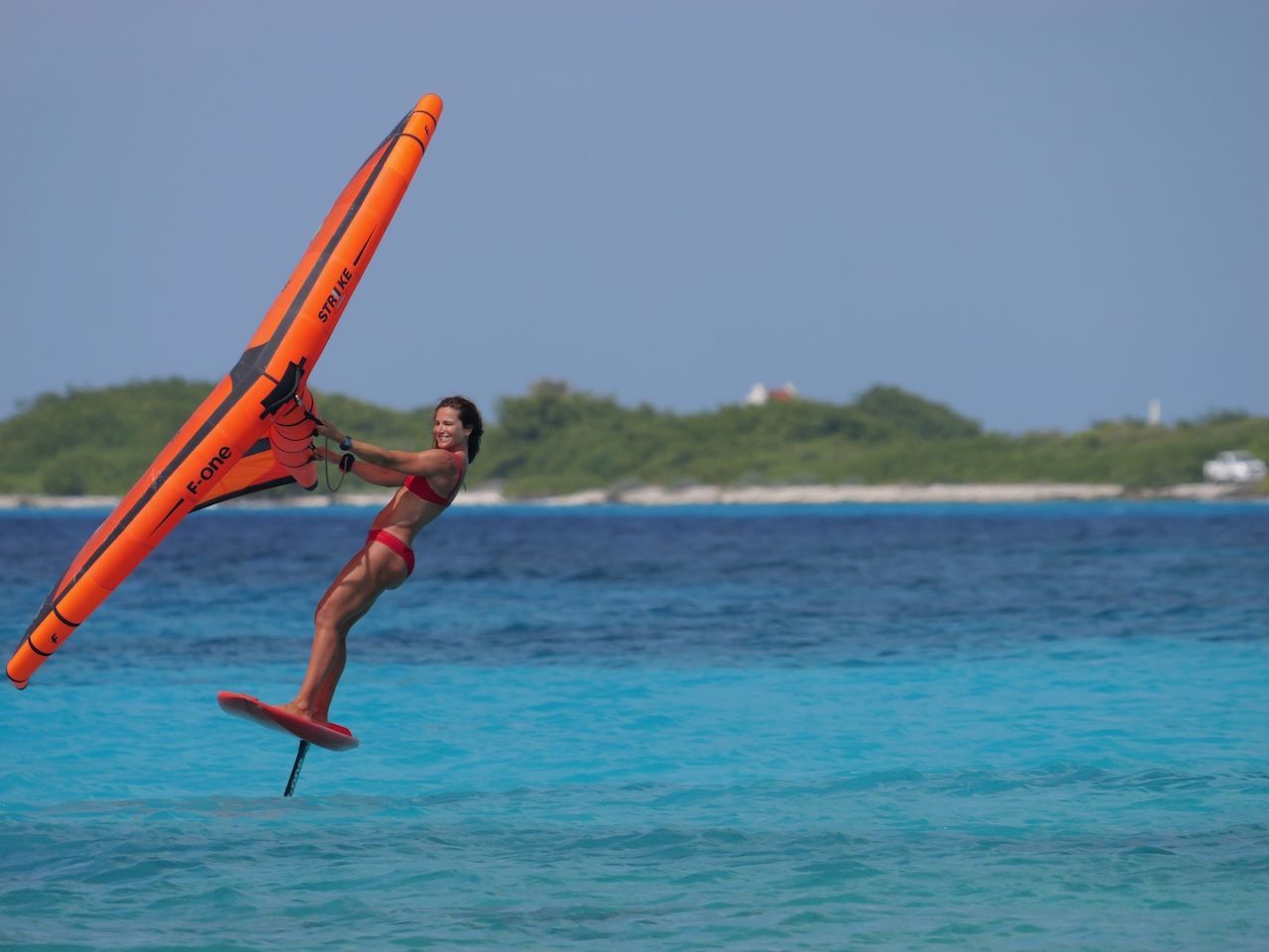 An aerial view of a person flying a kite in the ocean.