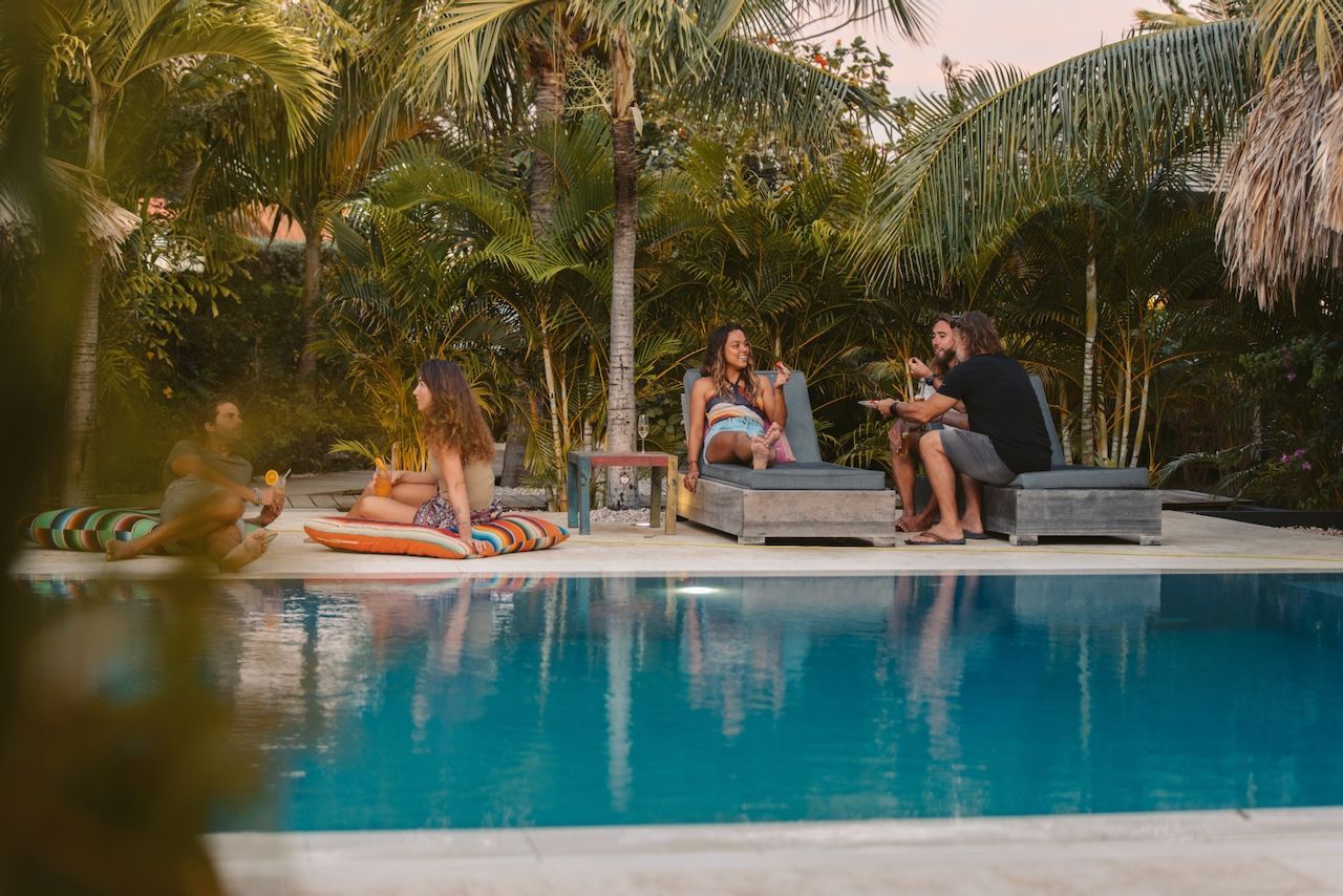 A group of people are sitting around a swimming pool.