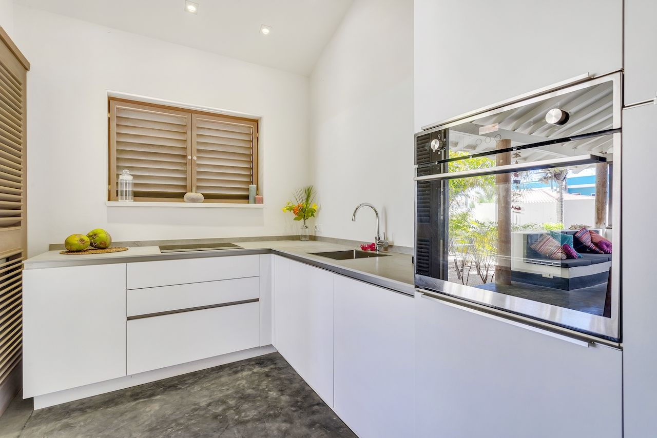 Una cocina con gabinetes blancos y electrodomésticos de acero inoxidable.