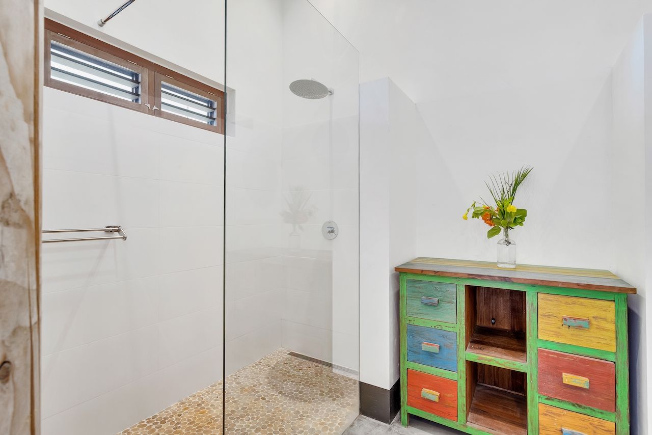 Een badkamer met inloopdouche en een kleurrijke ladekast.