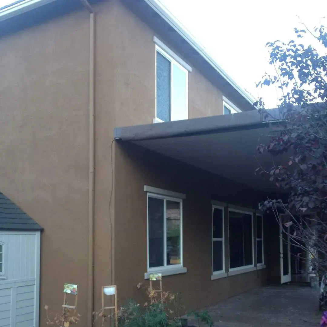 Tan stucco house exterior with a covered porch and white-trimmed windows