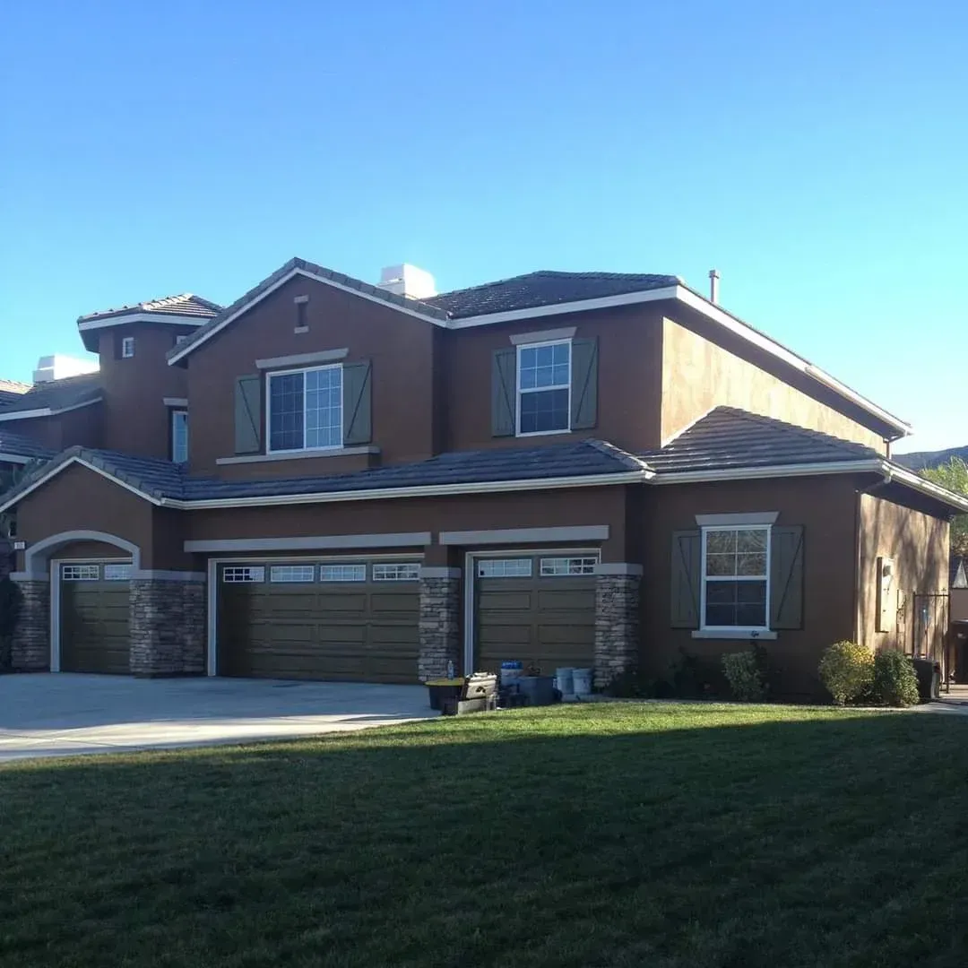 Two-story brick suburban house with a three-car garage and green lawn in daylight